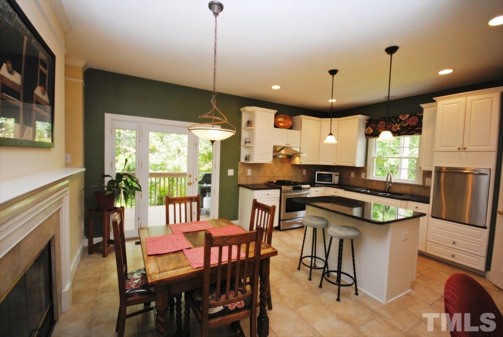 8805 Braceridge Road Raleigh, NC 27613 - Photo 11 of 25 a kitchen with stainless steel appliances granite countertop a stove a refrigerator a oven a sink with a dining table and chairs