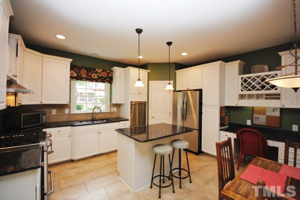 8805 Braceridge Road Raleigh, NC 27613 - Photo 12 of 25 a kitchen with stainless steel appliances granite countertop a refrigerator a sink dishwasher a stove and a dining table with chairs