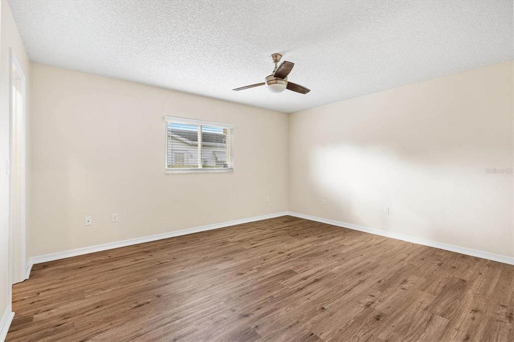 10767 Southeast 174th Loop Summerfield, FL 34491 - Photo 21 of 45 a view of an empty room with wooden floor and a ceiling fan