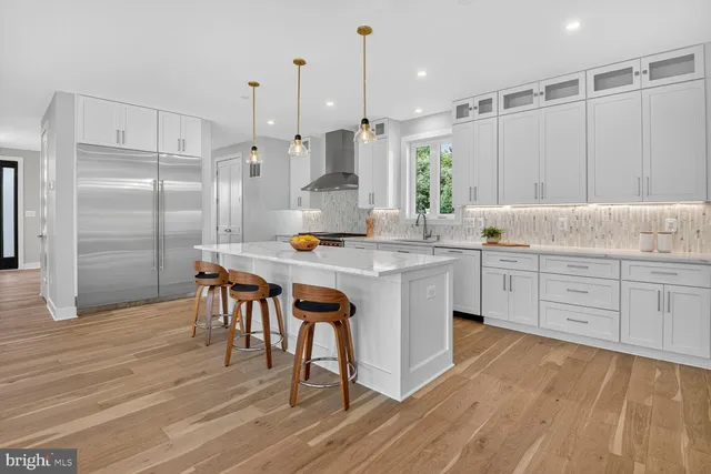 a large kitchen with stainless steel appliances kitchen island granite countertop a table chairs in it and wooden floors