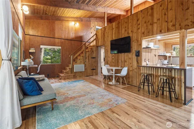 a living room with furniture a flat screen tv and floor to ceiling window
