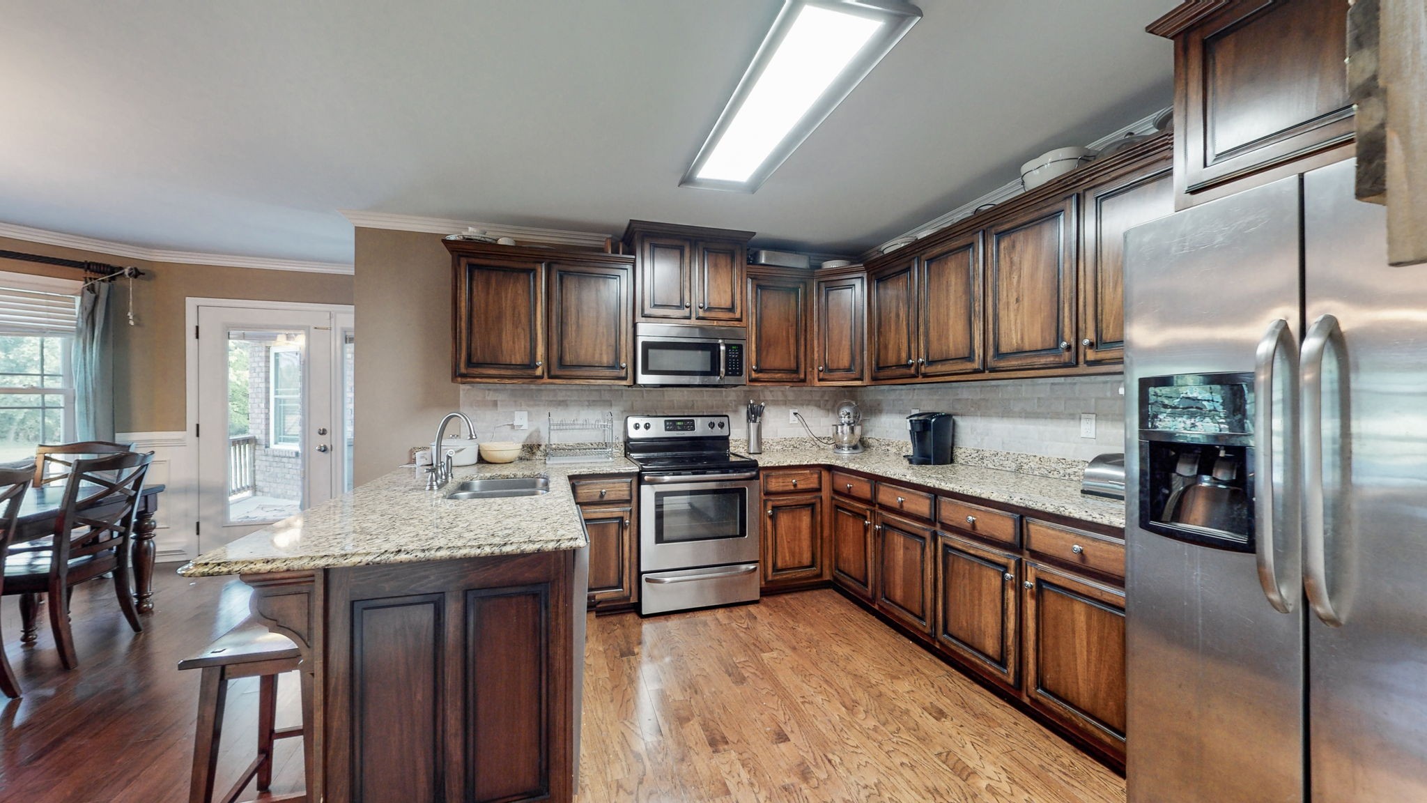 2870 Canoe Branch Road Lebanon, TN 37087 - Photo 18 of 45 a kitchen with stainless steel appliances granite countertop a stove top oven a sink dishwasher a dining table and chairs with wooden floor