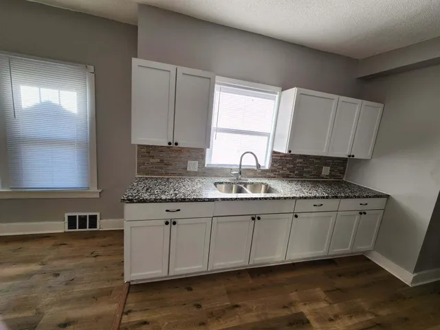 a kitchen with granite countertop a sink a stove and cabinets
