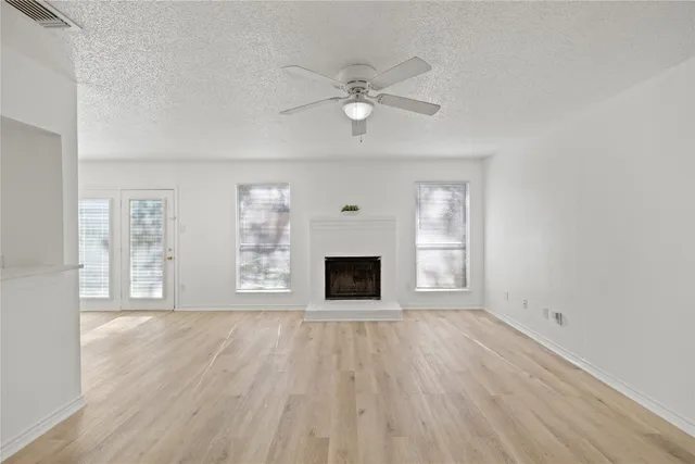 a view of a livingroom with wooden floor a ceiling fan and windows