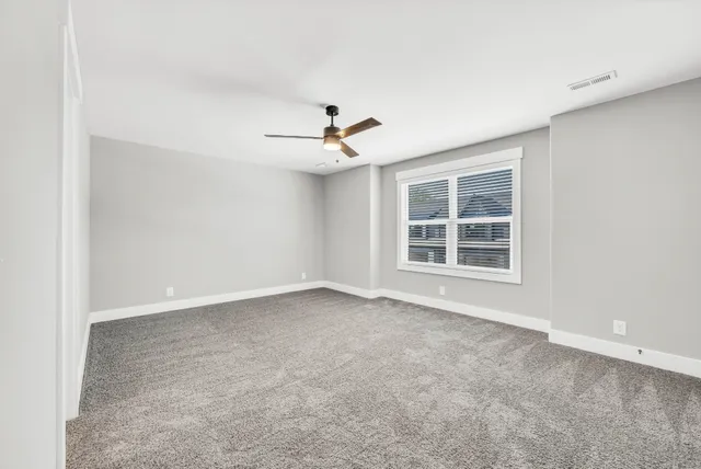 an empty room with windows and ceiling fan