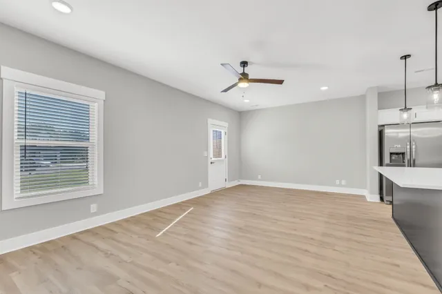 a view of empty room with wooden floor and fan