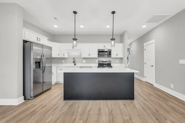 a large kitchen with stainless steel appliances a large counter top a refrigerator and a sink