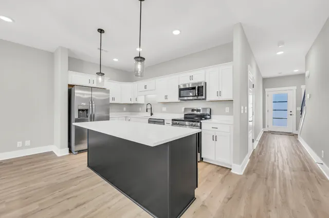 a kitchen with kitchen island a sink a center island a stove and a refrigerator