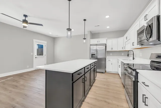 a kitchen with kitchen island a sink counter top space appliances and cabinets