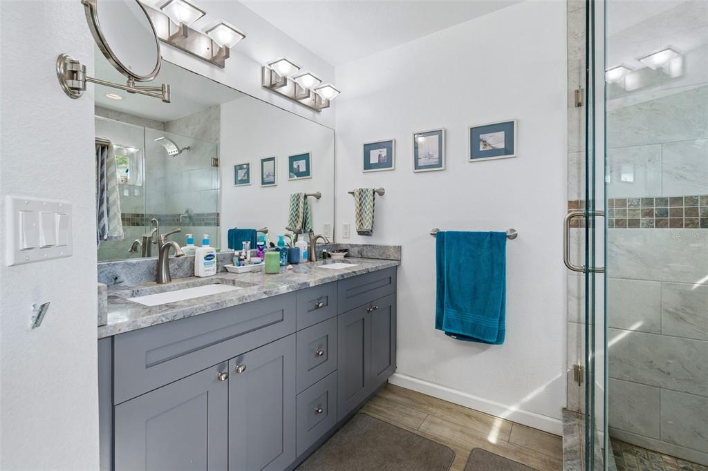 6226 8th Avenue South Gulfport, FL 33707 - Photo 21 of 46 a bathroom with a granite countertop sink a mirror and a shower