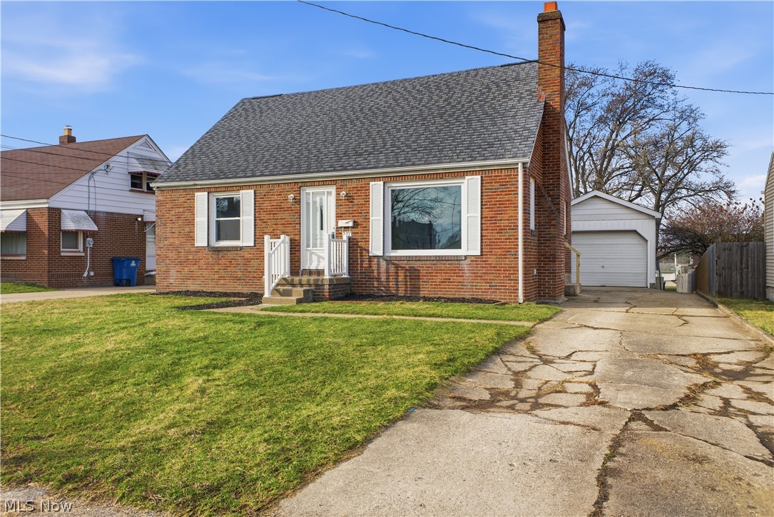 227 Wilson Street Struthers, OH 44471 - Photo 1 of 44 View of front facade featuring brick siding, a chimney, a shingled roof, a garage, and an outbuilding