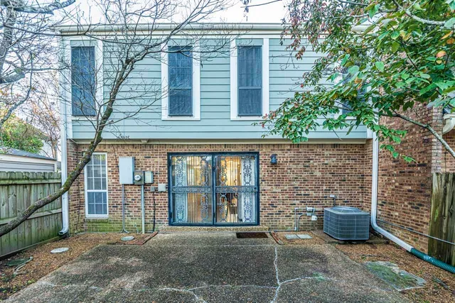 a view of a brick house with a large window and wooden fence