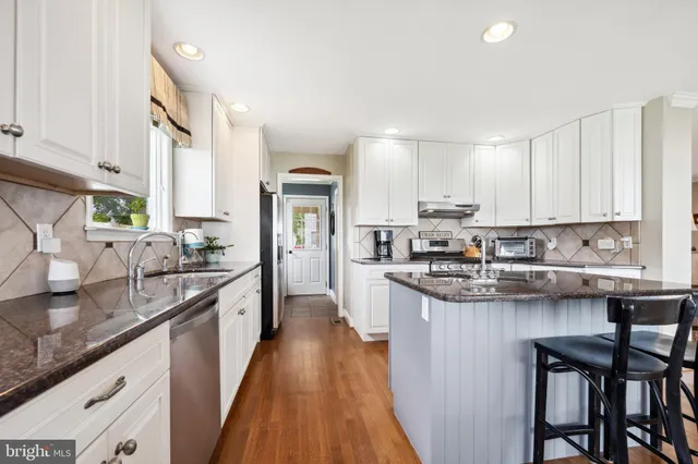 a kitchen with stainless steel appliances granite countertop a stove top oven a sink dishwasher and a refrigerator