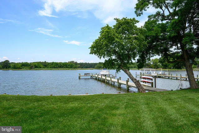 a view of a lake with table and chairs next to a yard