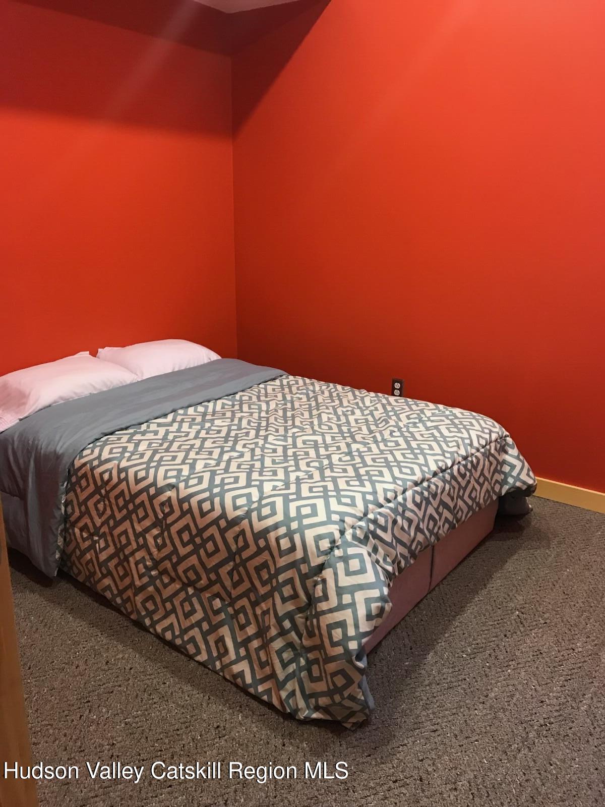 270 Pines Drive, Unit 92 Roxbury, NY 12421 - Photo 22 of 31 a bed sitting in a bedroom next to a blue wall