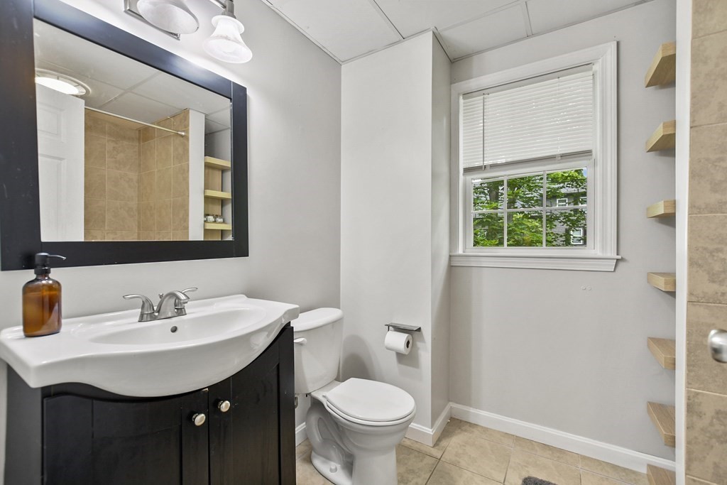 305 North Main Street Raynham, MA 02767 - Photo 30 of 38 a bathroom with a toilet a sink a mirror and a window