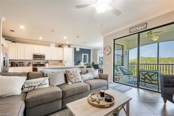 a living room with furniture kitchen view and a large window