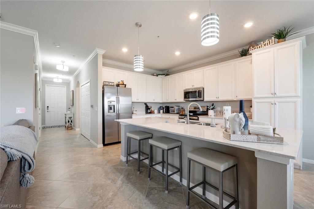 9572 Trevi Court, Unit 5045 Naples, FL 34113 - Photo 5 of 30 a kitchen with kitchen island a sink stainless steel appliances and cabinets