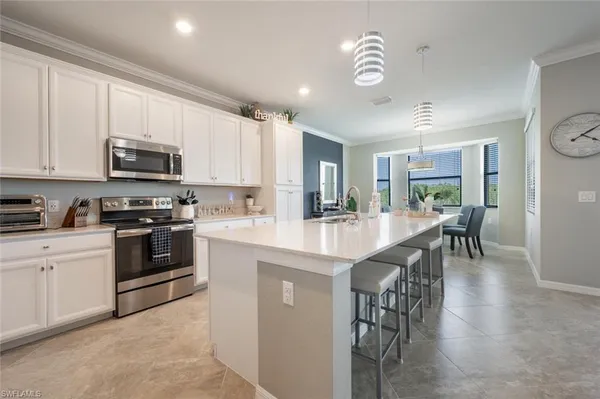 a kitchen with stainless steel appliances granite countertop a stove top oven a sink a dining table and chairs with wooden floor
