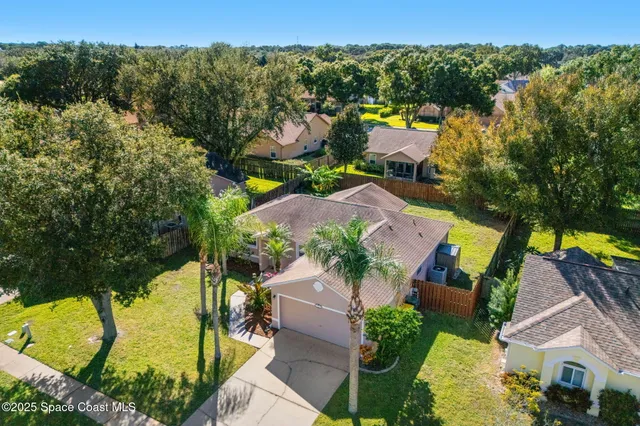 an aerial view of residential houses with outdoor space and trees