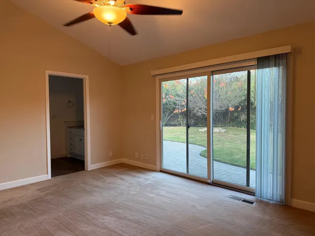 an empty room with chandelier fan and windows