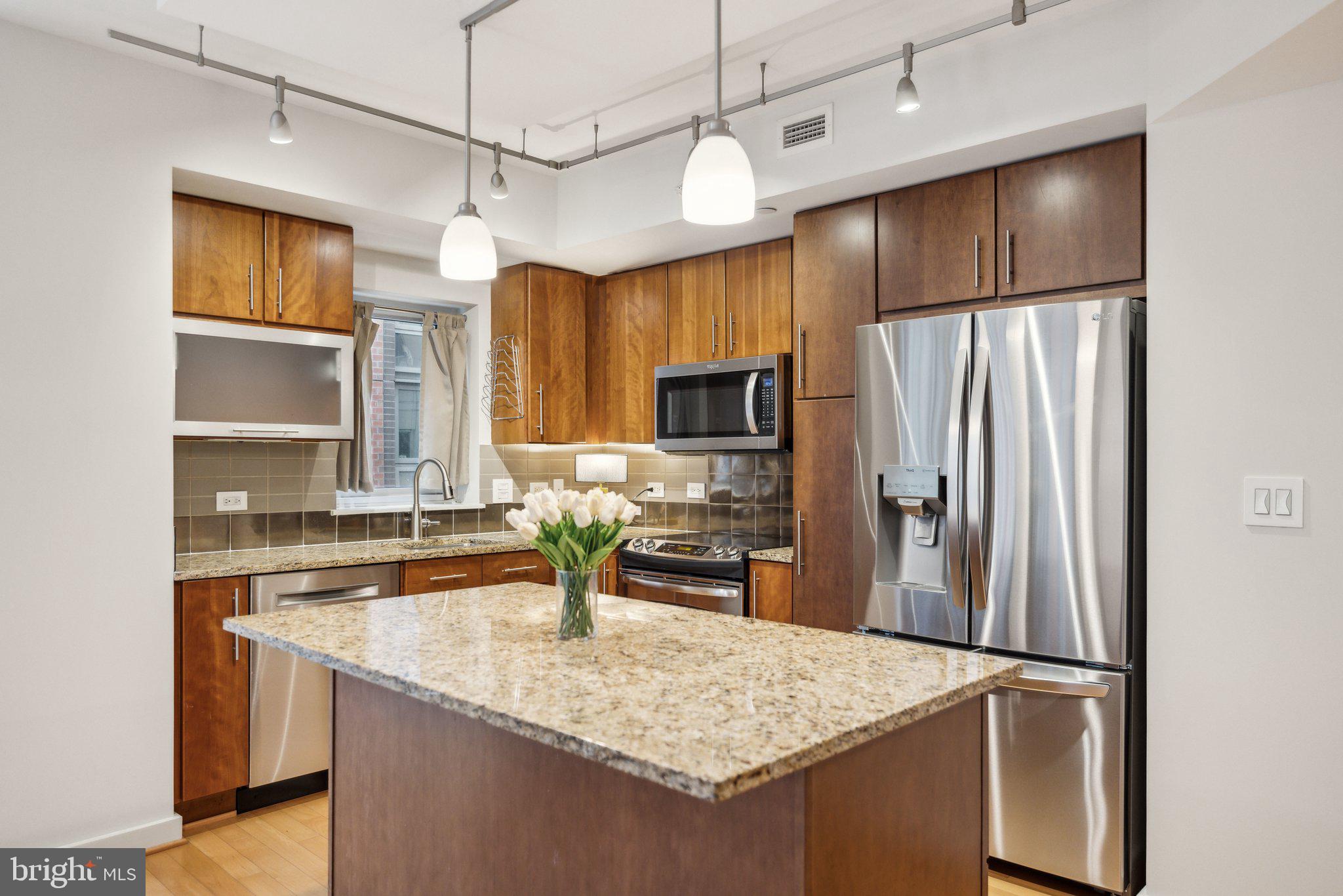 a kitchen with stainless steel appliances granite countertop a sink refrigerator and microwave