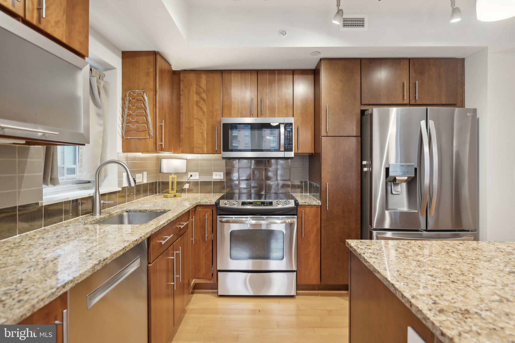 1025 First Street Southeast, Unit 716 Washington, DC 20003 - Photo 3 of 27 a kitchen with stainless steel appliances granite countertop a sink stove and refrigerator