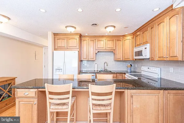 a kitchen with stainless steel appliances granite countertop a stove a sink and a refrigerator with wooden floor