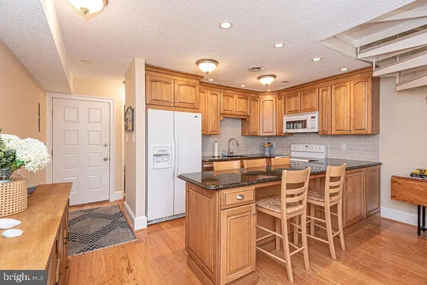 a kitchen with stainless steel appliances granite countertop a kitchen island hardwood floor sink and cabinets