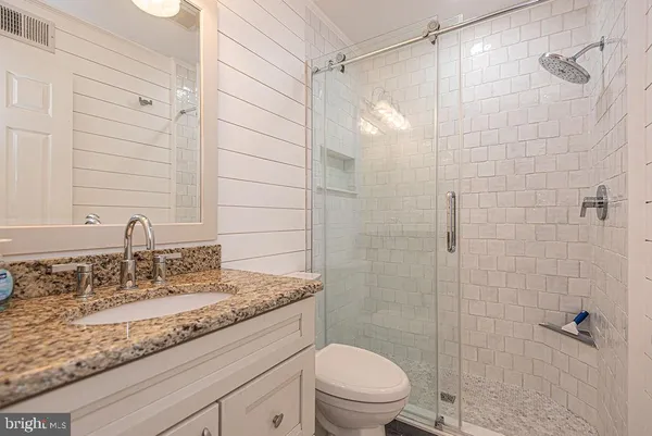 a bathroom with a granite countertop sink a toilet and shower