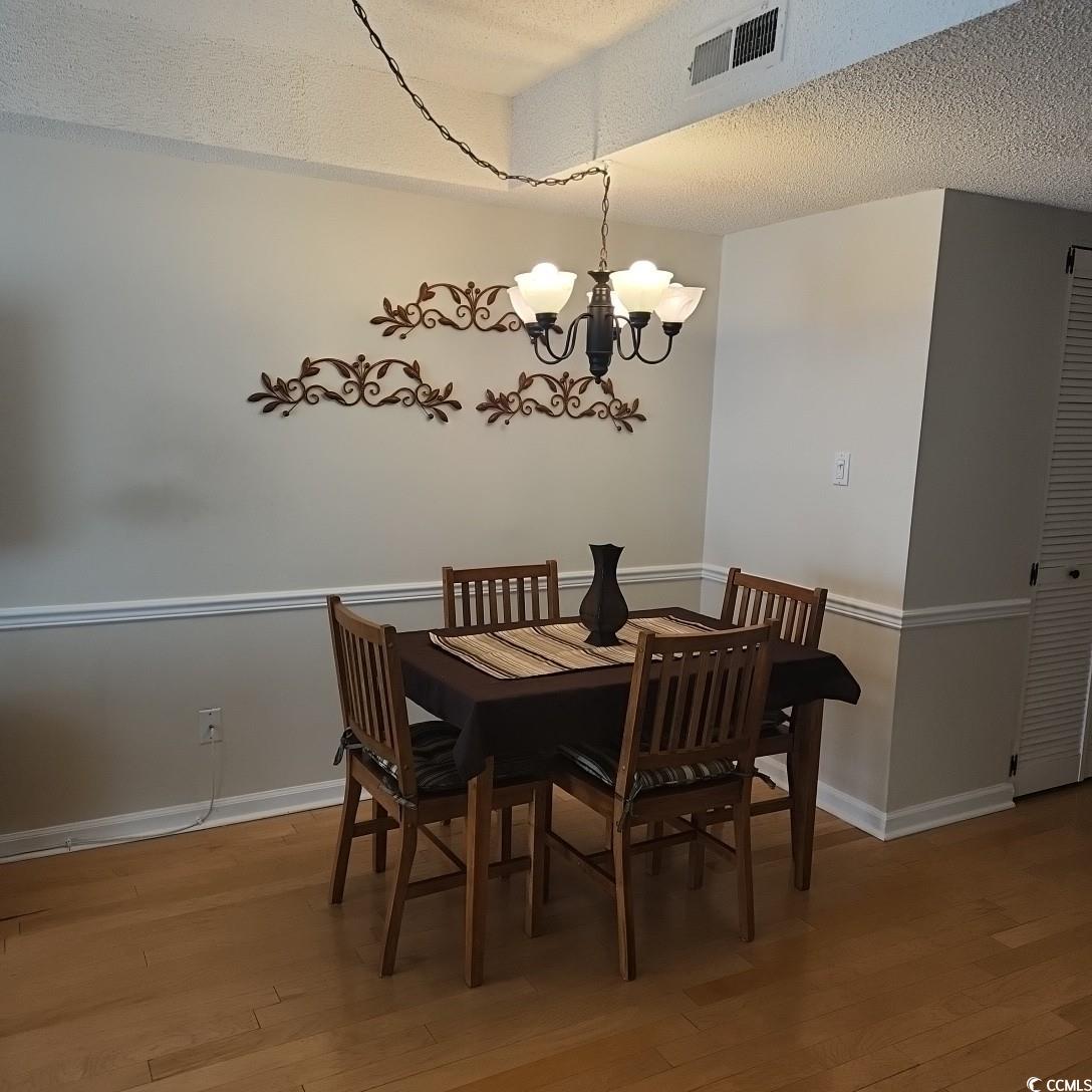 1300 Deer Creek Road, Unit C Surfside Beach, SC 29575 - Photo 7 of 18 Dining space with a textured ceiling, light wood-style flooring, and a chandelier