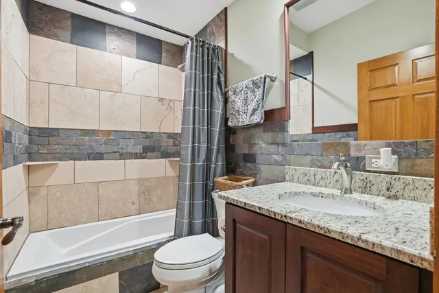 a bathroom with a granite countertop sink a toilet and bathtub