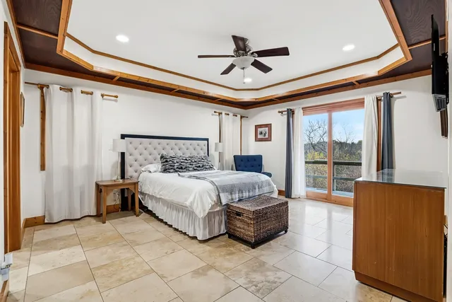 a bedroom with a bed ceiling fan and a large window