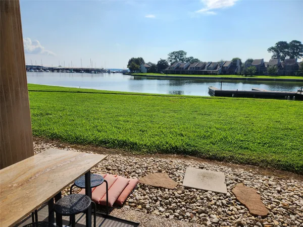 a view of a lake with a table and chairs in the patio next to a yard