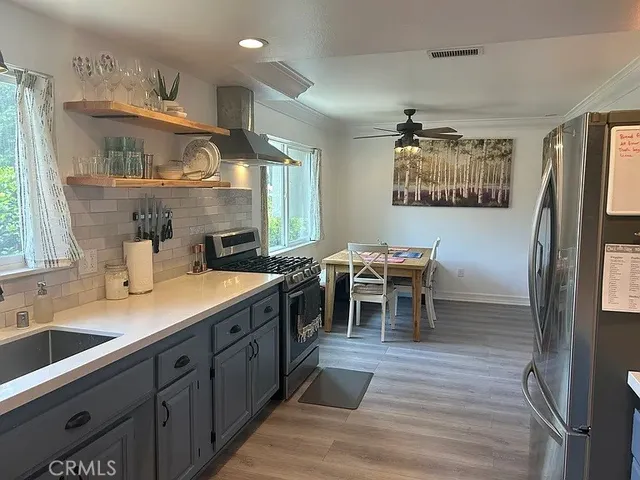 a living room with stainless steel appliances kitchen island granite countertop furniture a large window and a sink