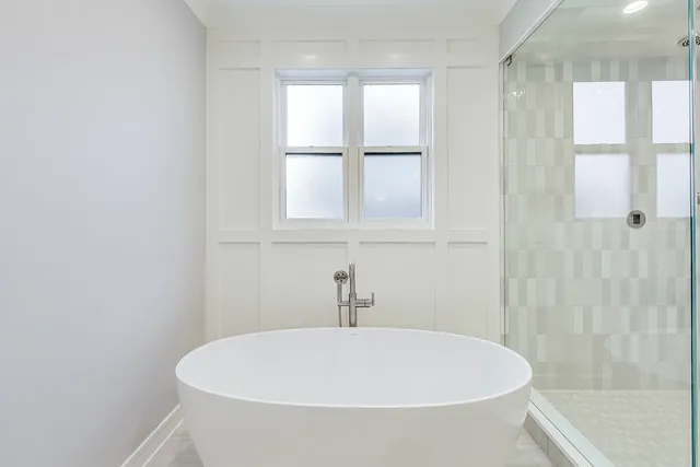 a white bath tub sitting in a bathroom next to a window