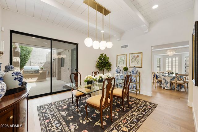 a view of a dining room with furniture a chandelier and large windows