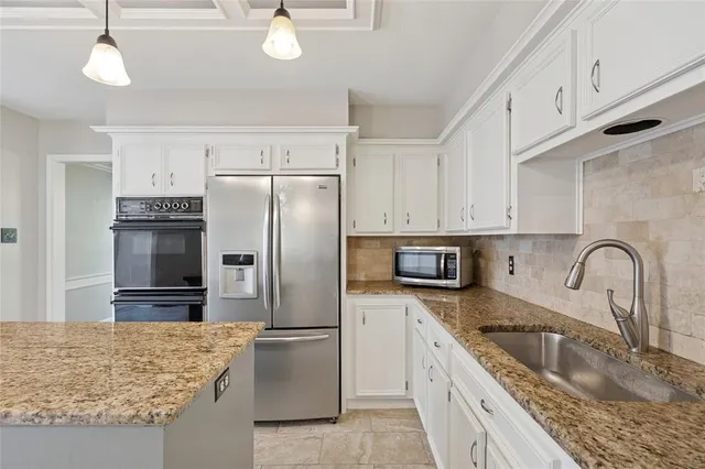 a kitchen with stainless steel appliances granite countertop a sink a refrigerator and a stove