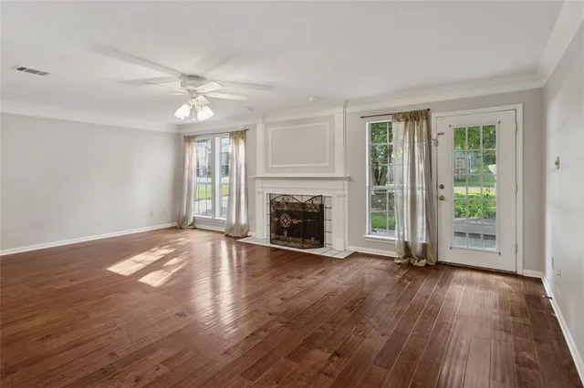 an empty room with wooden floor fireplace and windows
