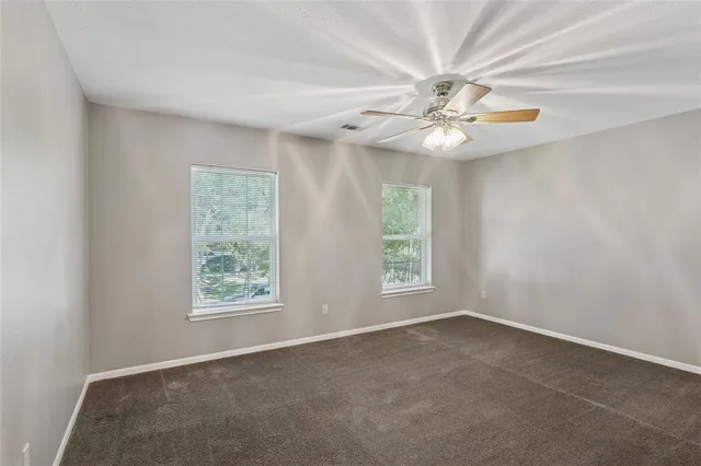 an empty room with windows and fan