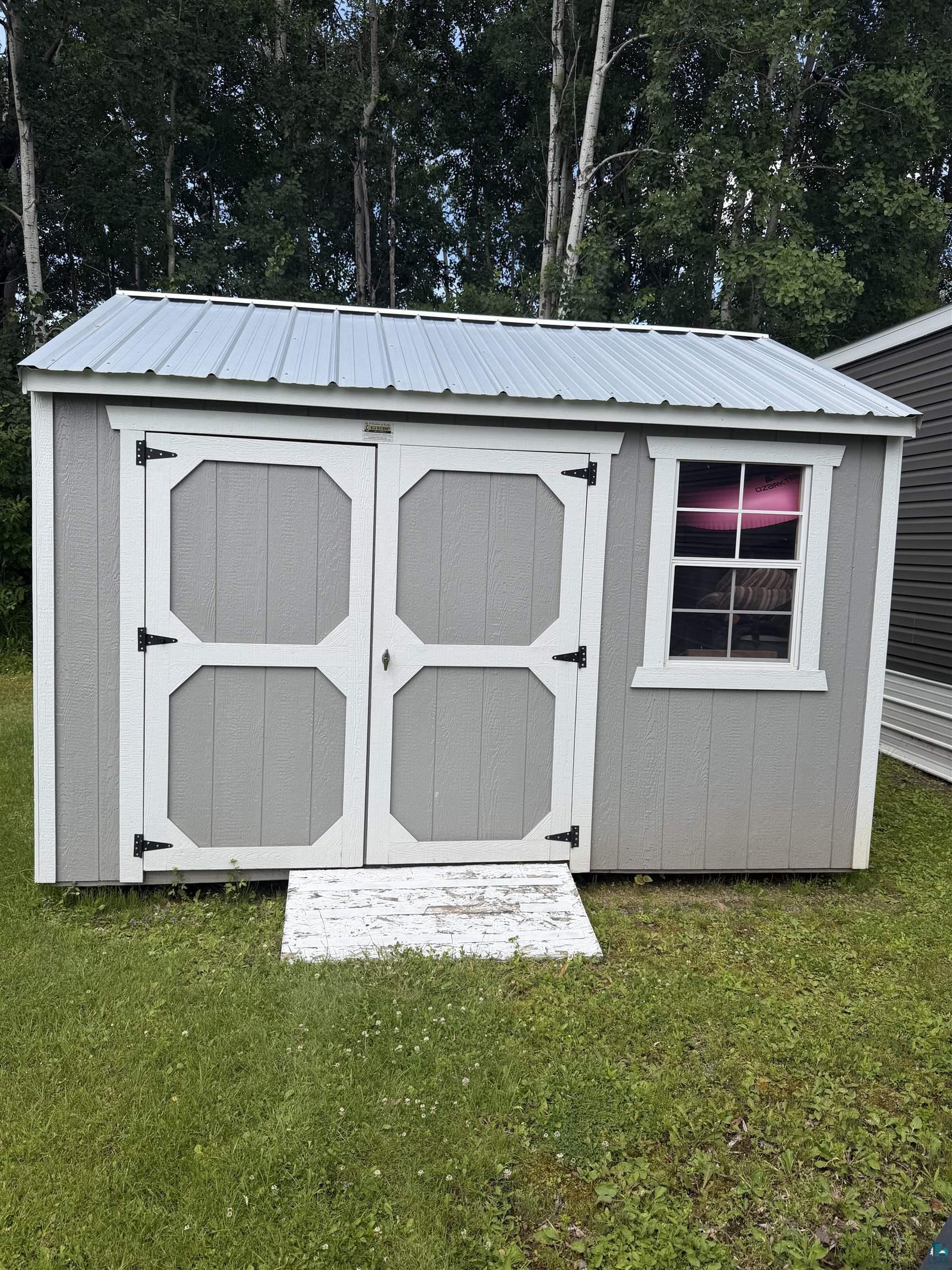 5051 Alpine Drive Hermantown, MN 55811 - Photo 5 of 24 Utility shed featuring a gray exterior siding, white trim, and a corrugated metal roof