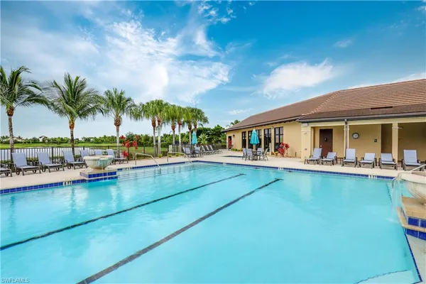a view of swimming pool with outdoor seating and house in the background