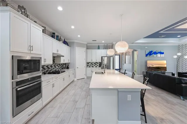 a large white kitchen with a sink and dishwasher a stove top oven with wooden floor