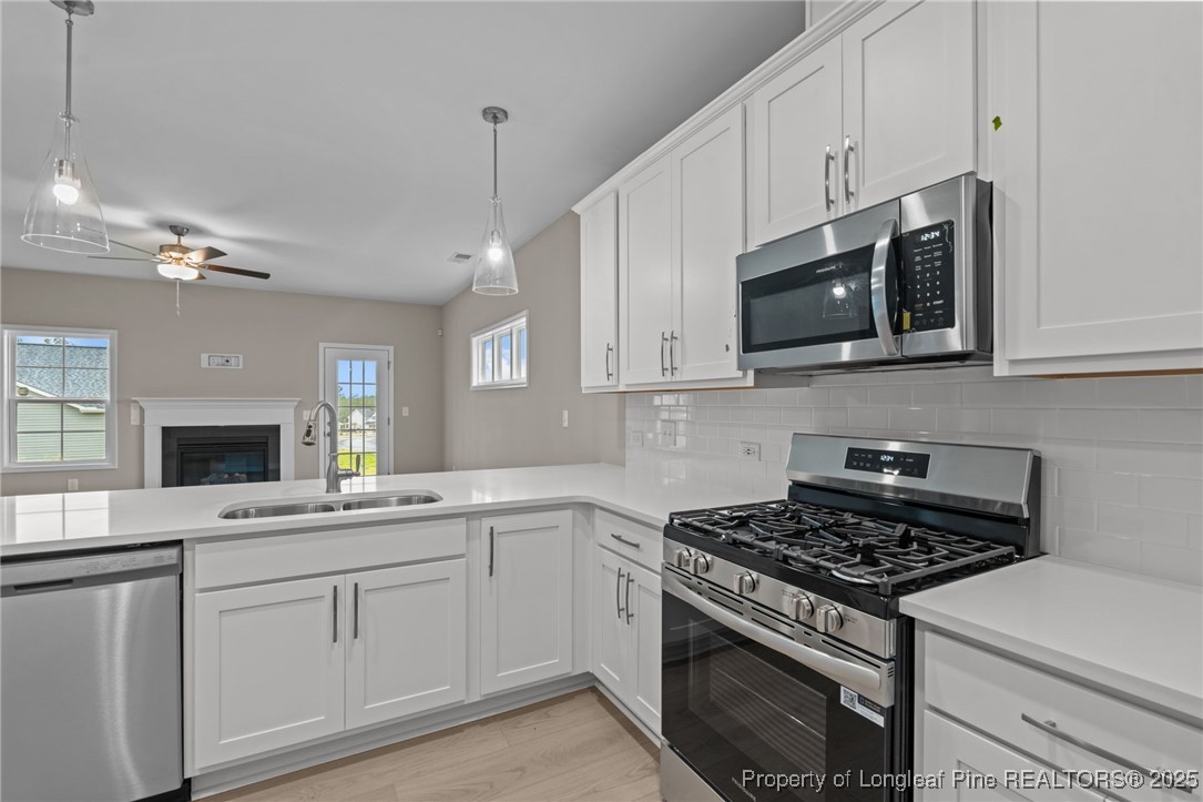 274 Rough Ridge Trail Aberdeen, NC 28315 - Photo 13 of 47 a kitchen with stainless steel appliances white cabinets and a stove top oven