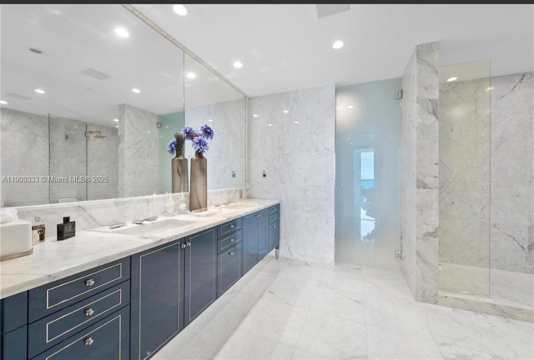 9349 Collins Avenue, Unit 304 Surfside, FL 33154 - Photo 31 of 40 a bathroom with a granite countertop sink a large mirror and shower