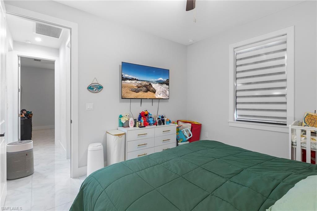 2406 37th Avenue Northeast Naples, FL 34120 - Photo 16 of 29 Bedroom featuring light marble finish floors and a ceiling fan