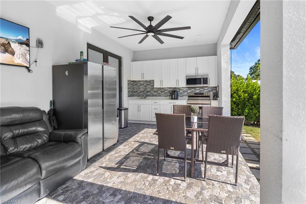 2406 37th Avenue Northeast Naples, FL 34120 - Photo 24 of 29 Kitchen with light countertops, white cabinetry, appliances with stainless steel finishes, decorative backsplash, and a ceiling fan