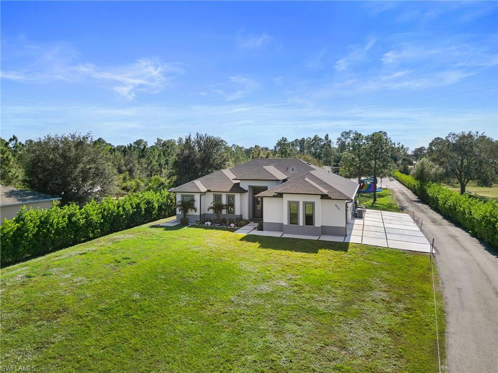 2406 37th Avenue Northeast Naples, FL 34120 - Photo 26 of 29 View of front of home featuring stucco siding, a front lawn, and a shingled roof
