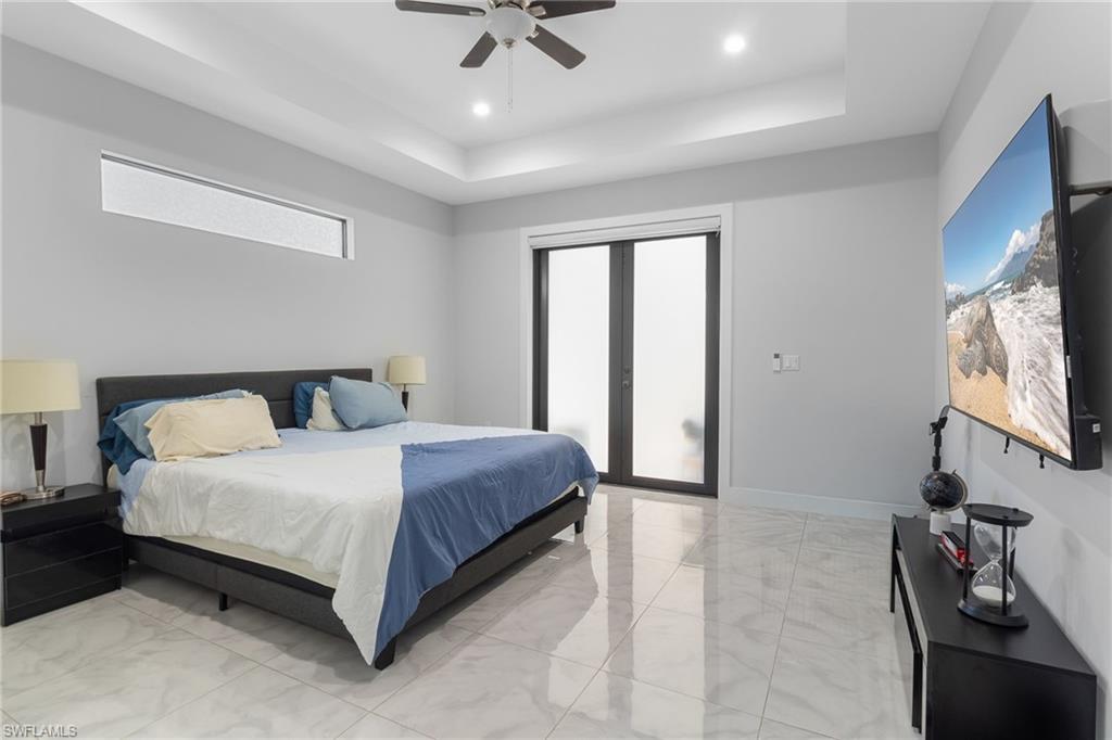 2406 37th Avenue Northeast Naples, FL 34120 - Photo 8 of 29 Bedroom with access to exterior, light marble finish floors, a tray ceiling, a ceiling fan, and recessed lighting