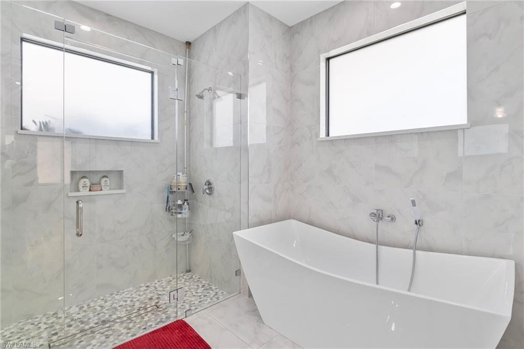 2406 37th Avenue Northeast Naples, FL 34120 - Photo 10 of 29 Bathroom with a freestanding tub, plenty of natural light, a marble finish shower, marble finish floors, and tile walls